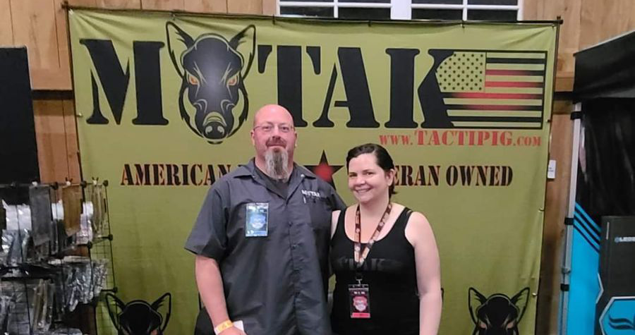 Founders of MOTAK LLC standing in front of their trade show booth with the company banner, showcasing their American Veteran-Owned business